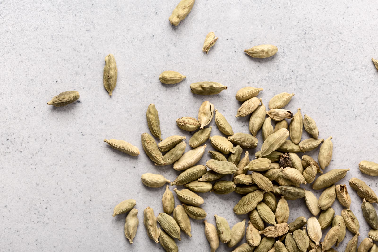 High angle of natural seeds concept (scattered green cardamom pods)