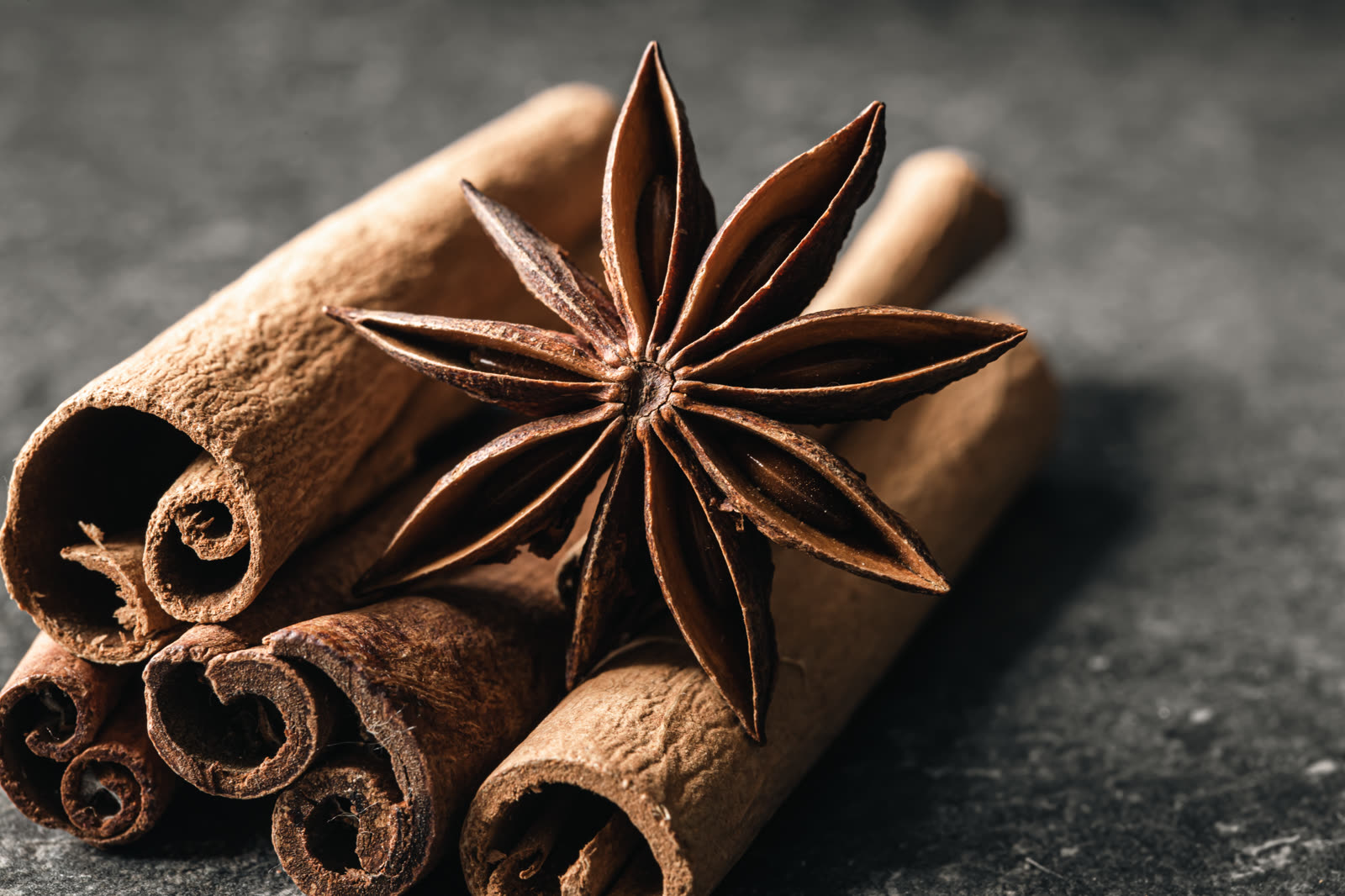 Aromatic cinnamon sticks and anise on black table close up
