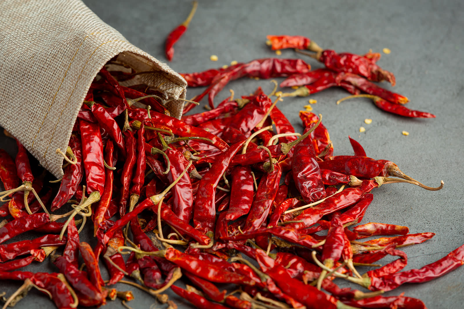 Dried chili pepper pouring out from sack to floor
