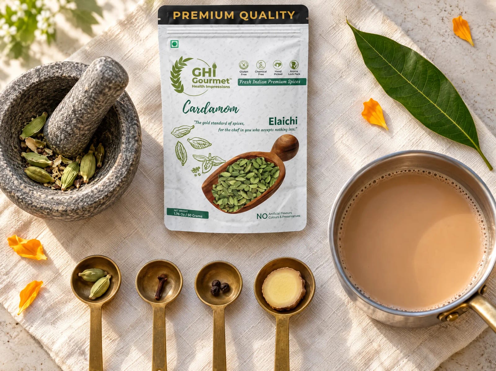Per cup chai spices in brass spoons beside a GHI cardamom pouch and mortar