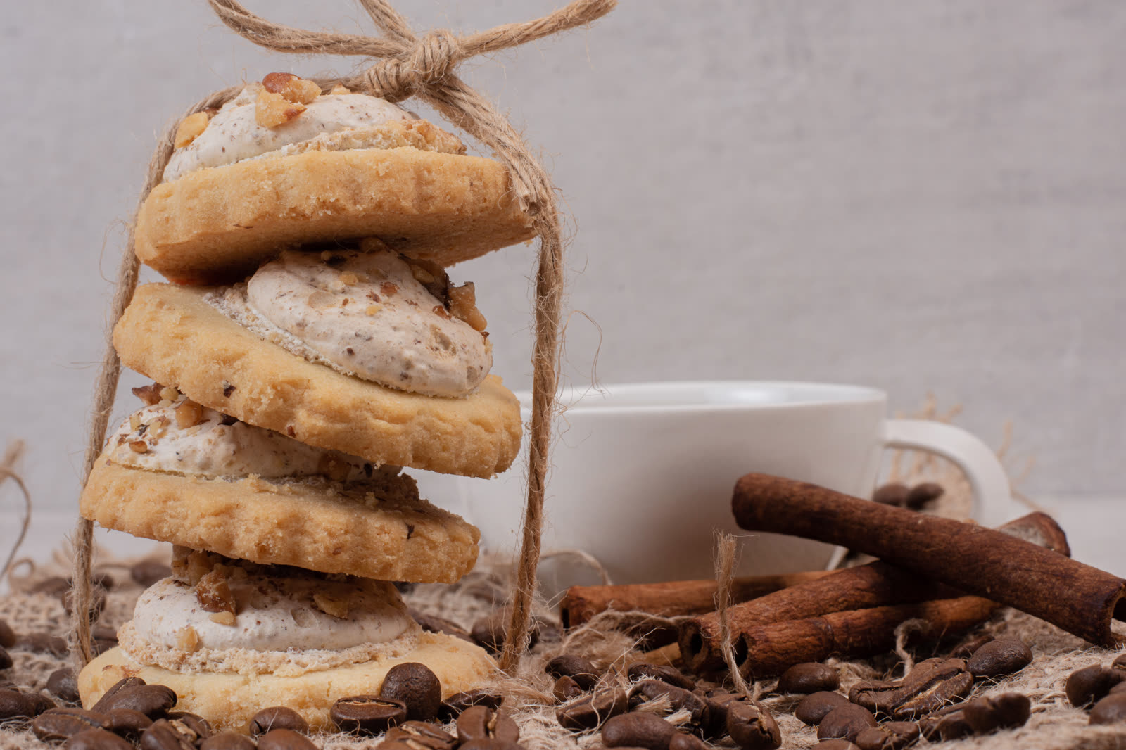 Stack of oatmeal cookies, cup and cinnamon on white table